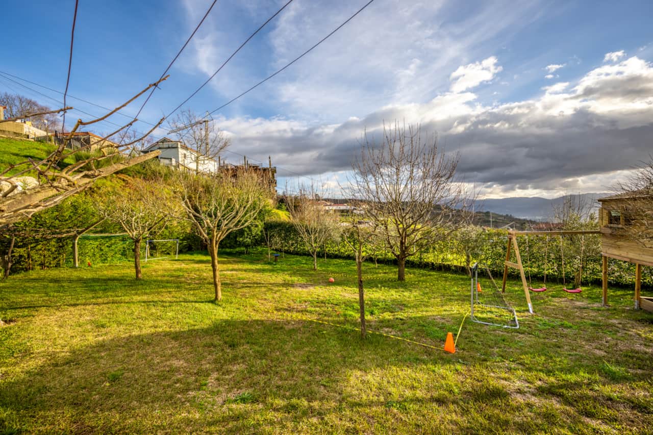 Zona infantil dedicada, com casa de madeira, baloiço e escorrega.