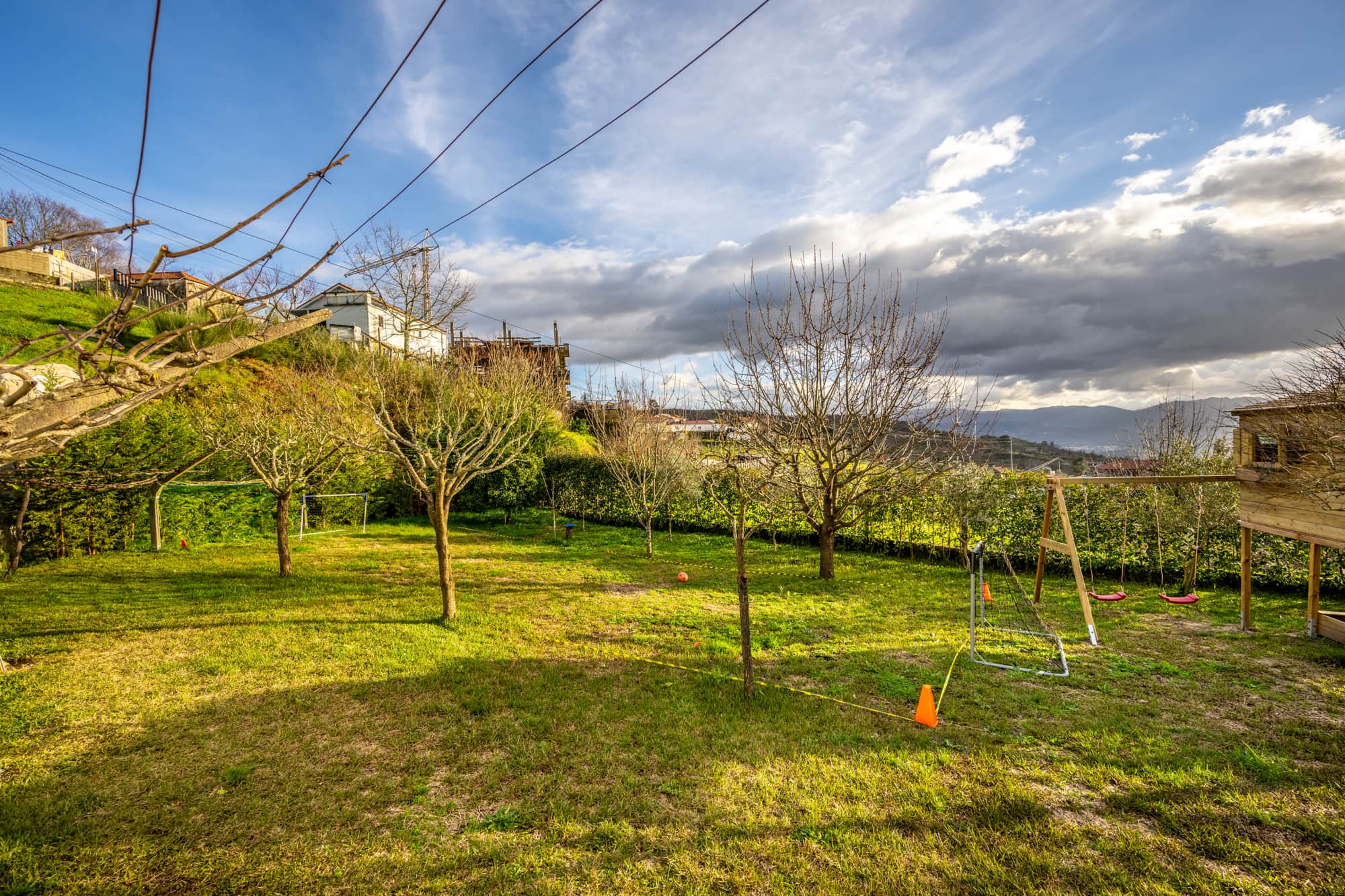 Zona infantil dedicada, com casa de madeira, baloiço e escorrega.