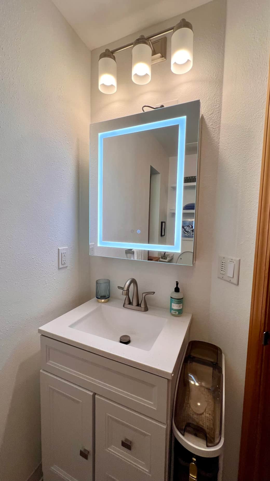 Modern medicine cabinet with lighted mirror, touch controls for dimming, color change, and defogger.