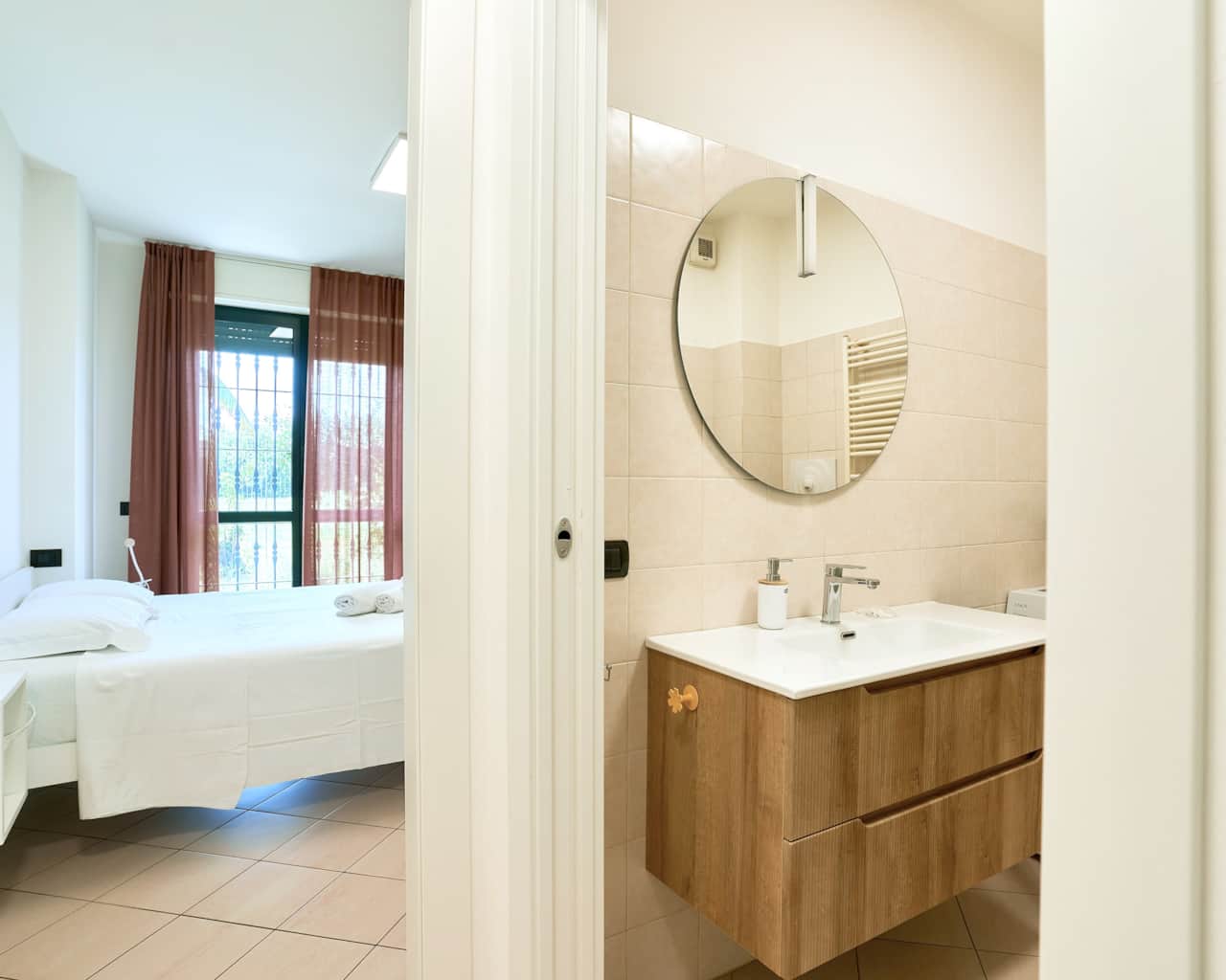 Baño con lavabo de madera, espejo redondo y luz natural