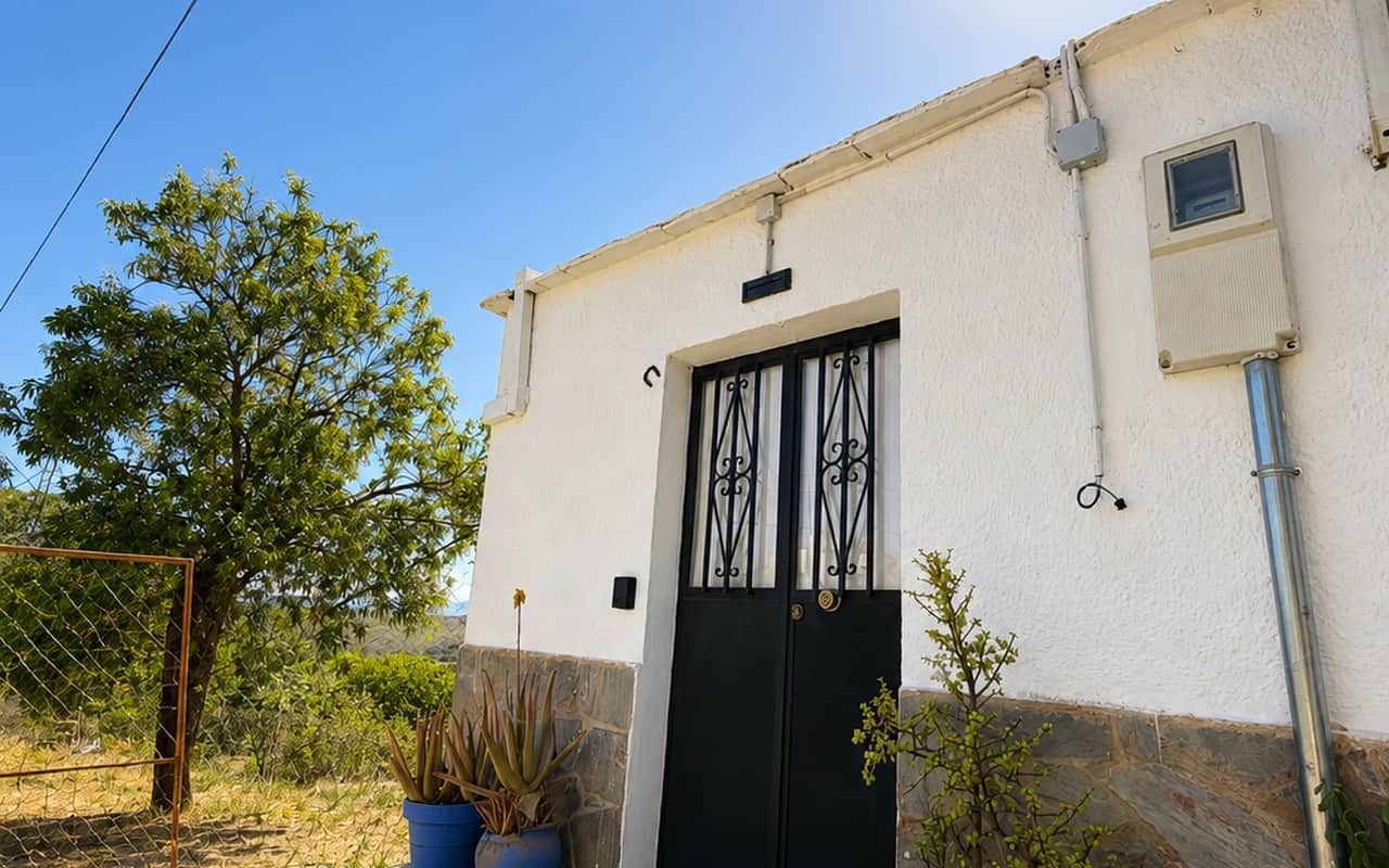 Fachada blanca de La Casilla con su puerta de forja negra, en Gérgal
