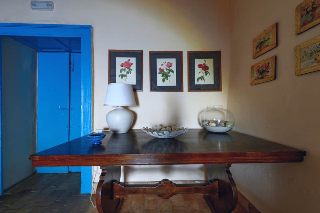 Angolo living con tavolo in legno e dettagli decorativi tipici delle case eoliane Angolo living con tavolo in legno e dettagli decorativi tipici delle case eoliane