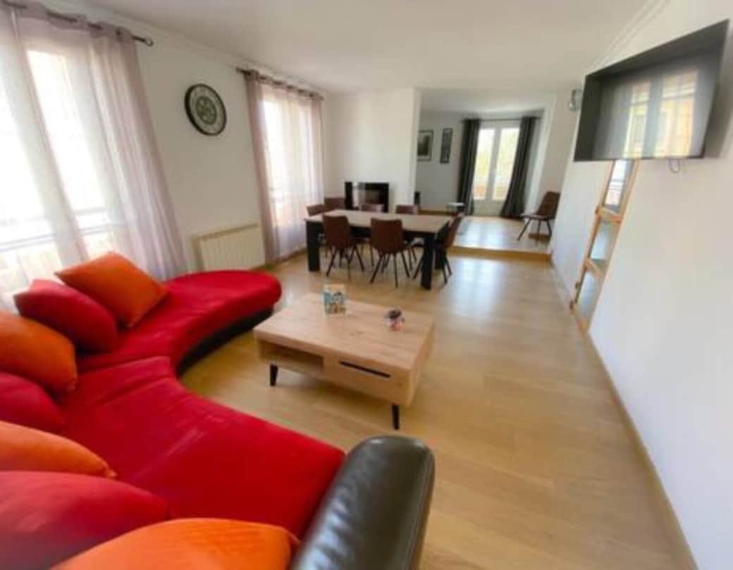 Séjour lumineux avec canapé-lit, TV et table à manger conviviale.
