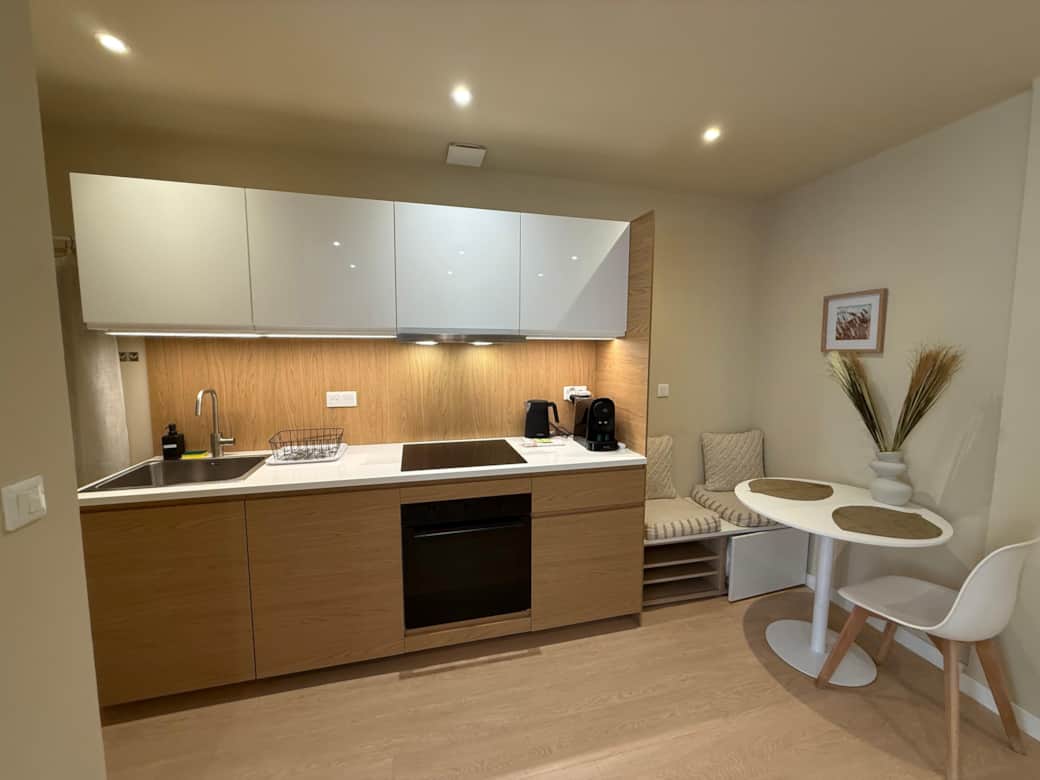 Fully equipped kitchen with oven, induction hob, kettle, coffee machine, and storage.