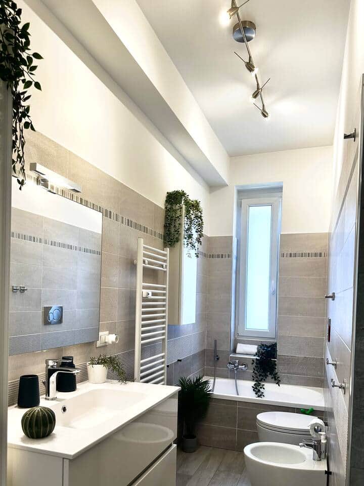 The elegant windowed bathroom, with its quality materials, offers a spacious shower and a small bathtub for moments of relaxation.