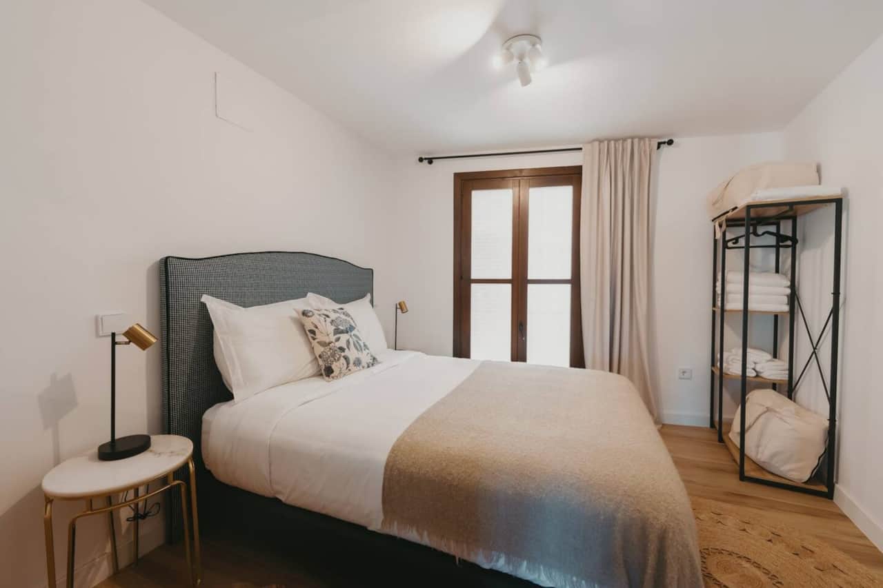 Dormitorio con cama doble, cabecero tapizado y balcón