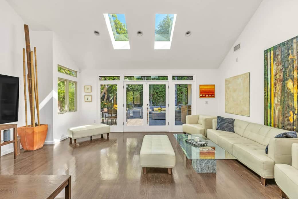 Sun-drenched living area featuring dual skylights and wide French doors opening to the patio.