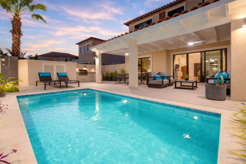 private backyard by night with pool, BBQ, and pagoda-covered dining and lounging areas