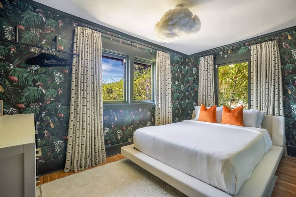 Cozy queen bedroom with lush garden views and bold jungle wallpaper—a private, dreamy retreat.