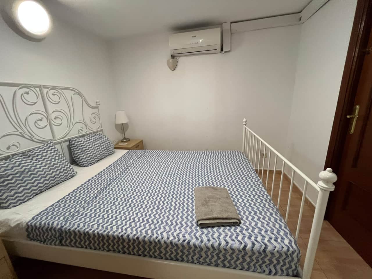 Bedroom with wrought-iron double bed, bedside table and air conditioning