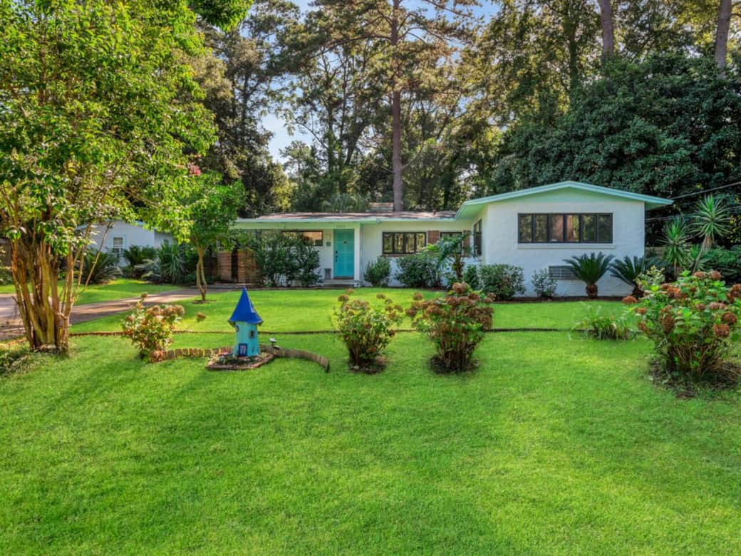 Front view.  Surrounded by mature shade trees.