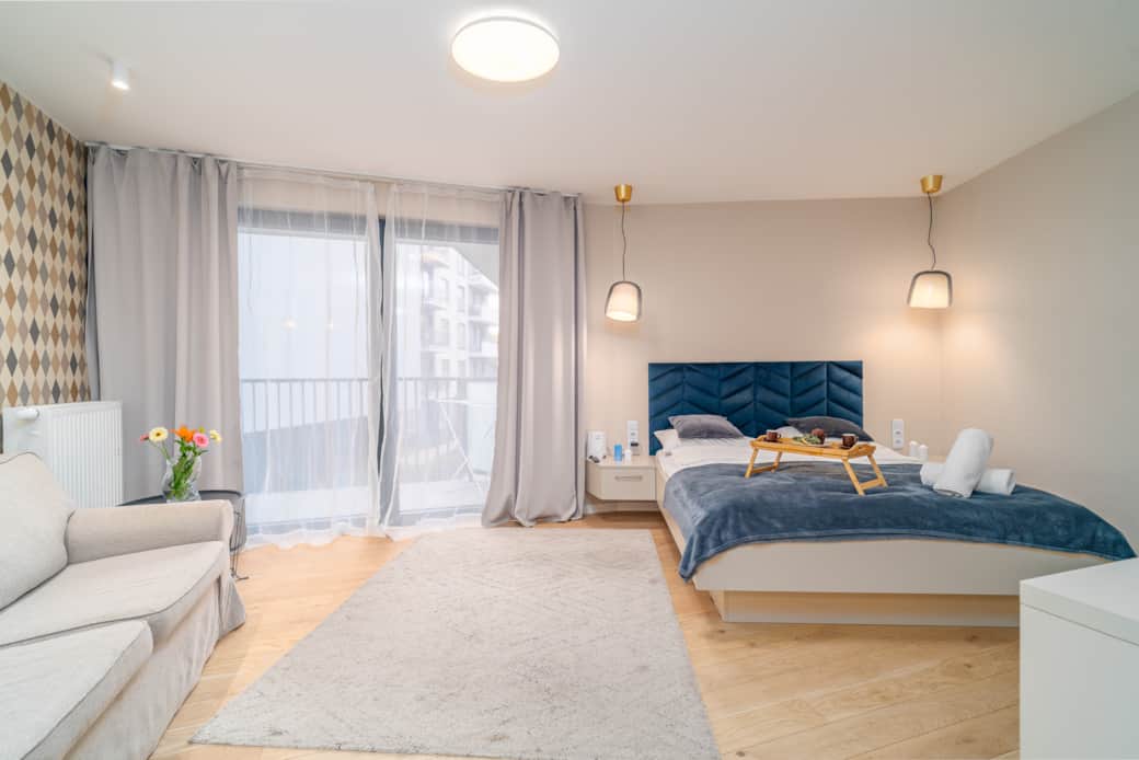 Przestronny pokój z dużym łóżkiem, sofą i wyjściem na balkon.