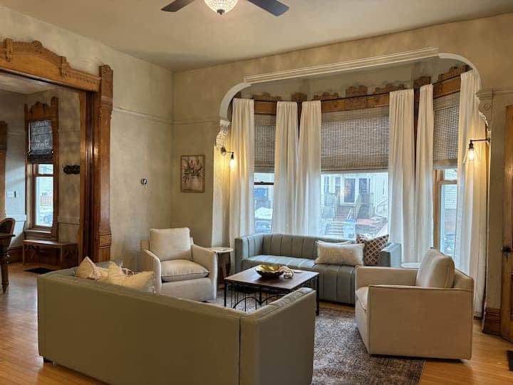Inviting living room with plush seating, large bay windows, and warm natural light.