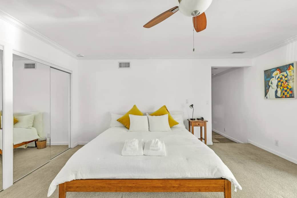 The primary bedroom features a California King bed with fresh linens and a sleek ceiling fan.