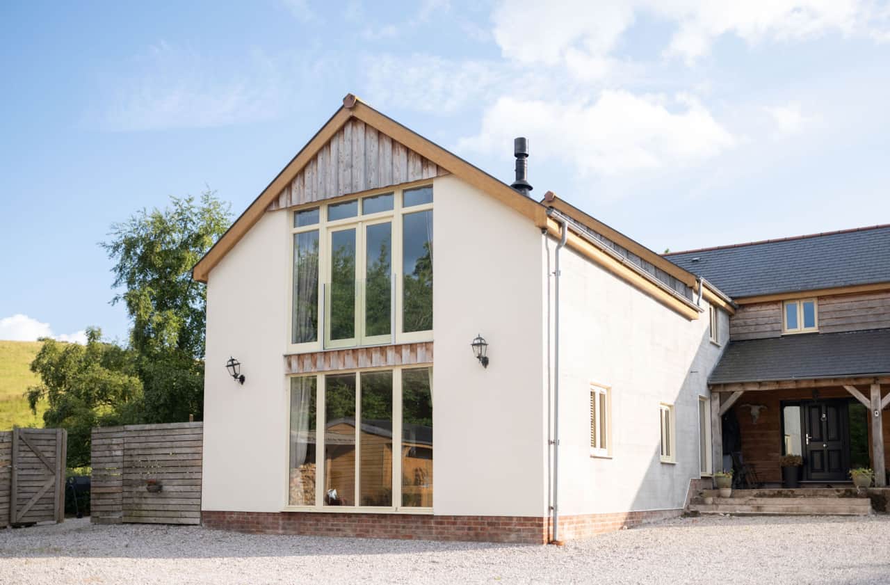 Modern holiday home exterior with large windows and rustic touches.