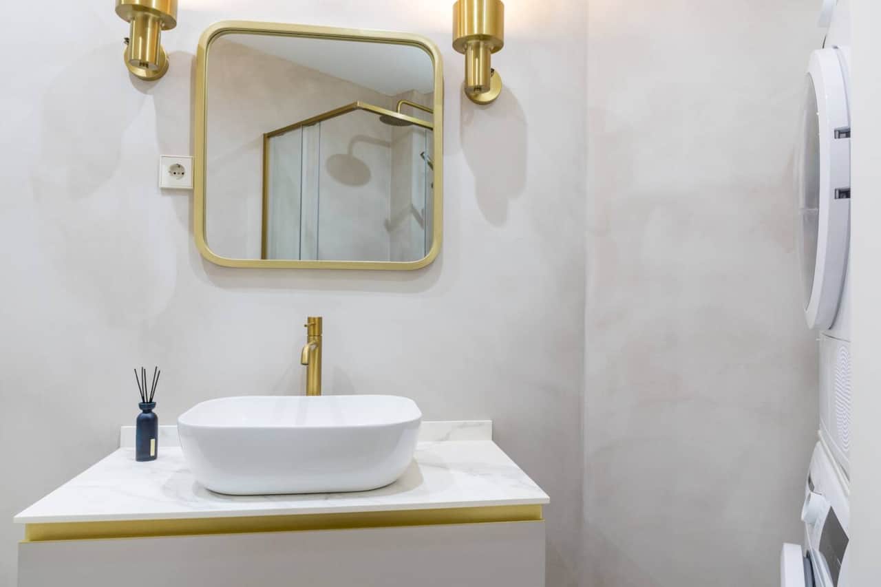 Baño reformado con lavabo sobre encimera y espejo con apliques