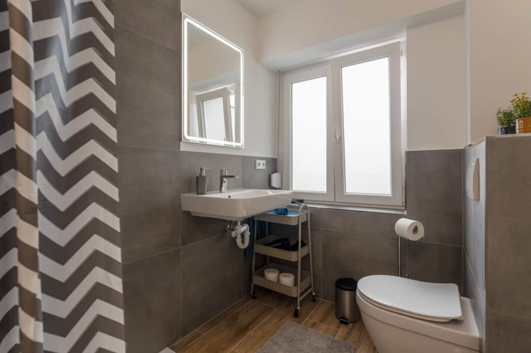 Kompaktes Badezimmer mit Fenster und Regendusche.