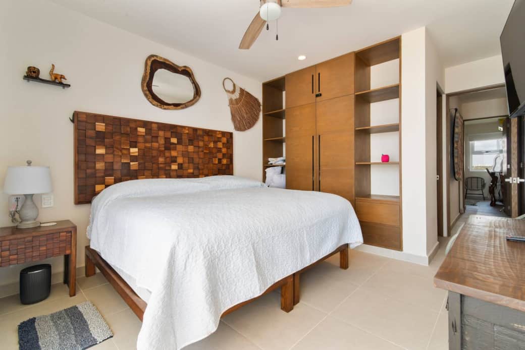 Elegant bedroom with wardrobe, smart TV, A/C, fan, and private bathroom.