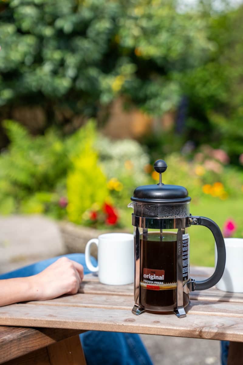 A cafetiere and mugs on the wooden garden table