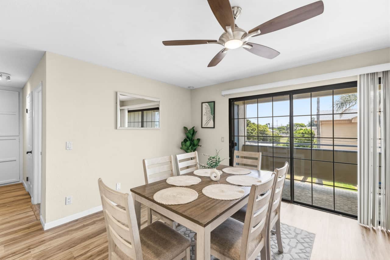 Bright dining area with seating for 6, hardwood floors, and a sliding door leading to balcony