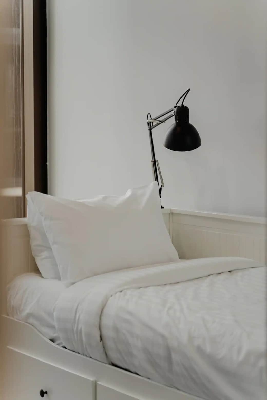 Immerse yourself in the tranquility of our meticulously designed bedroom. The pristine white bedding and elegant black desk lamp create a harmonious blend of comfort and sophistication. This space is perfect for those seeking a peaceful retreat.