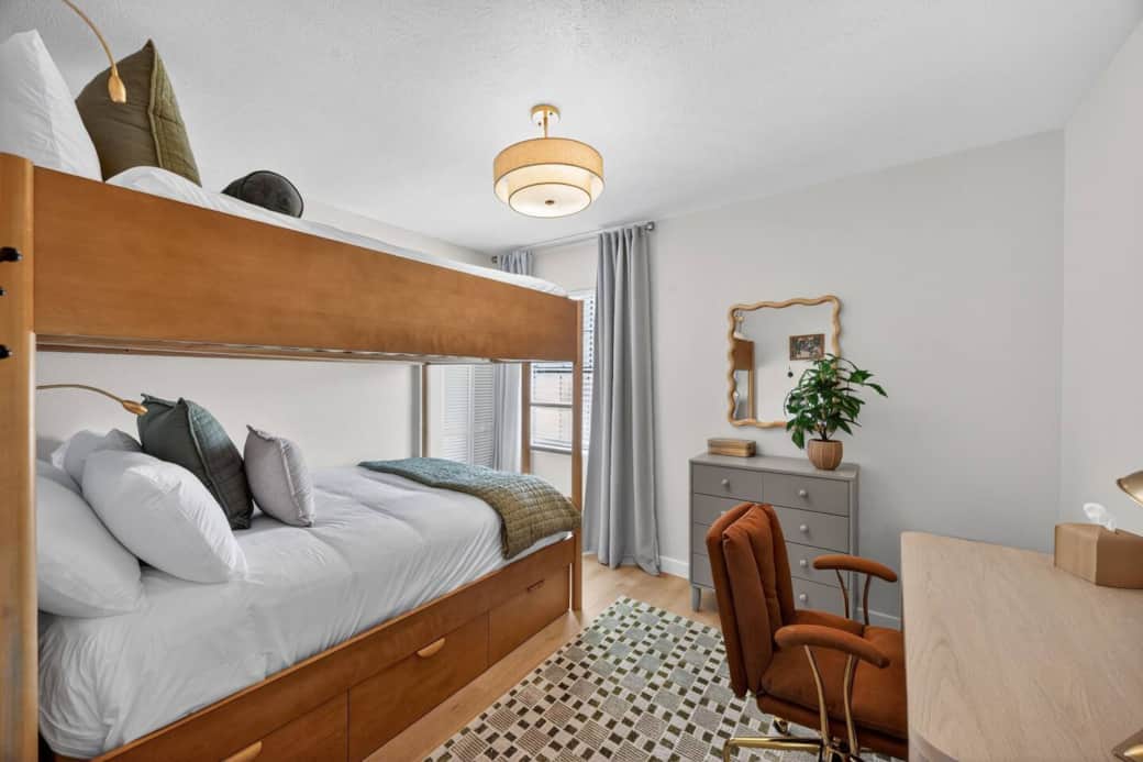 Full over full bunk beds in a spacious room with work space and dresser in addition to under bed storage.