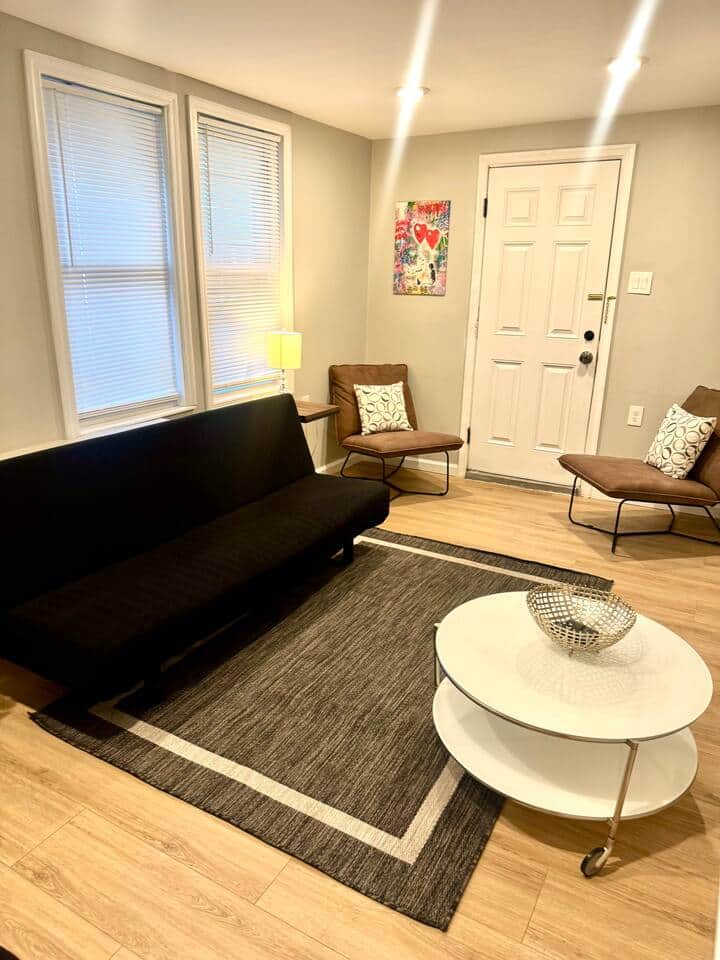 Discover our elegantly designed living room, featuring two versatile futon sofa beds, a large flat-screen television, and a cozy fireplace, providing an ideal setting for both relaxation and social gatherings.