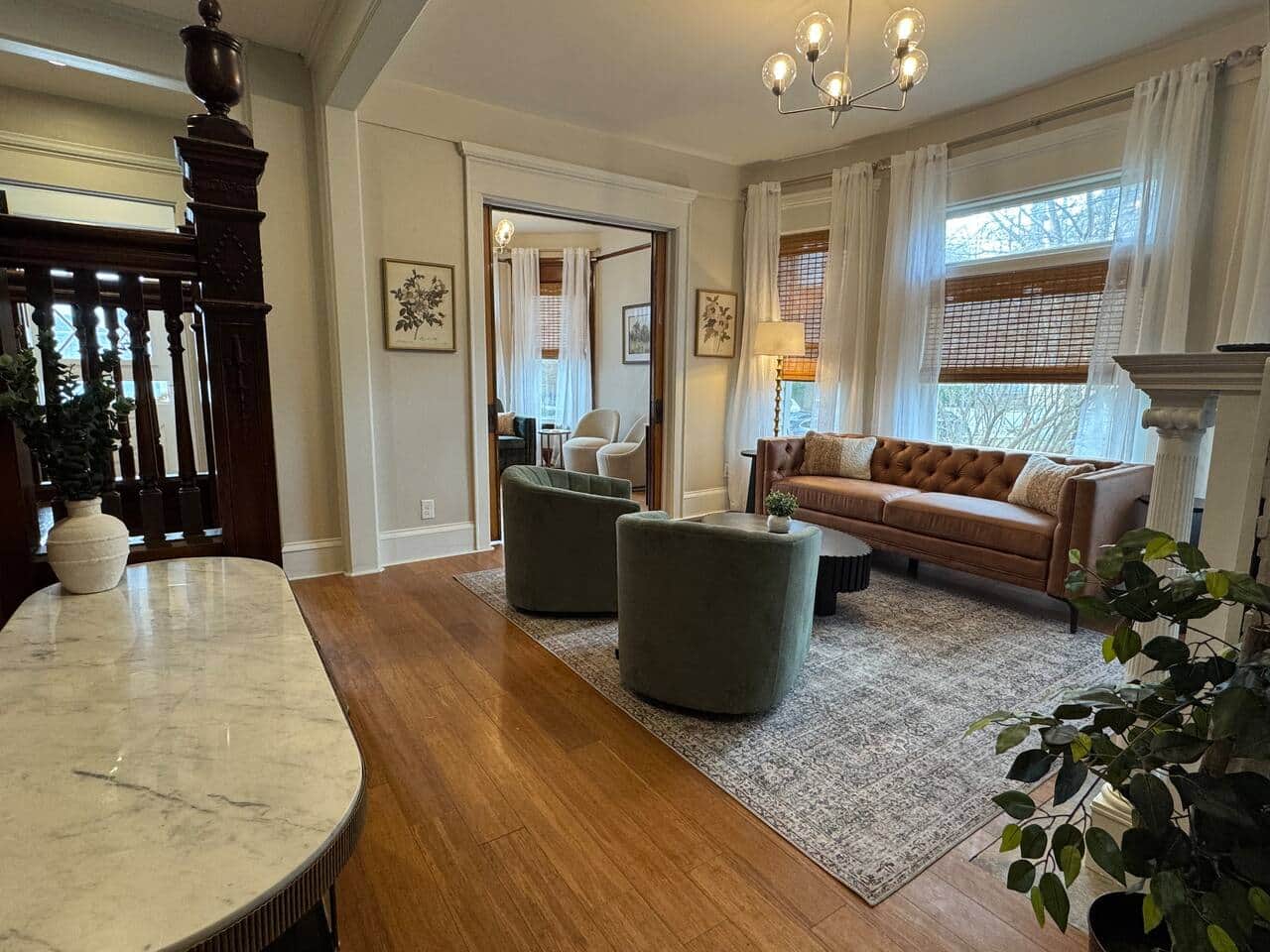 Bright and inviting living space with large bay windows, soft sheer curtains, and natural light.
