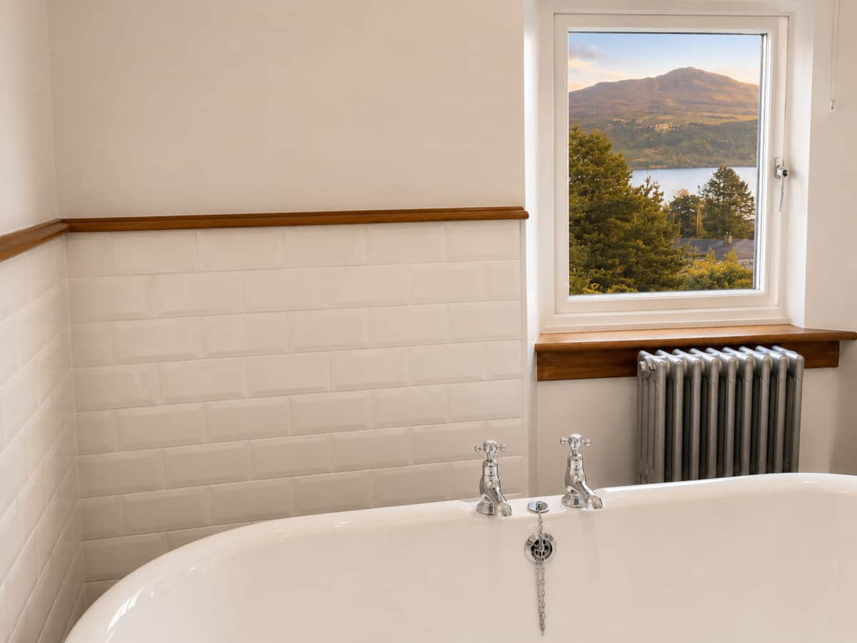 Freestanding bath beneath a window framing the hills of the Isle of Skye.