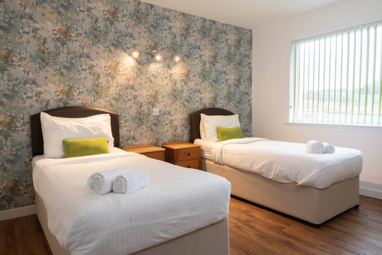 Two single beds with a bedside table, perfect for families, friends, or loved ones to share a room.