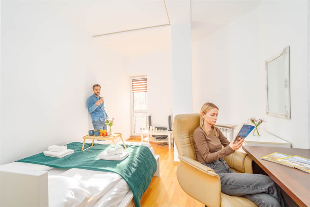 Jasny, przytulny pokój z dużym oknem i drewnianą podłogą.