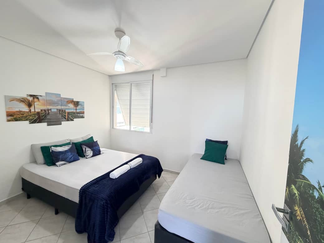 Quarto com cama de casal, cama de solteiro ambiente espaçoso.