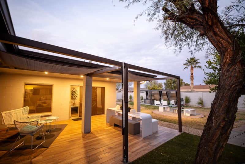 Covered backyard patio with dining and lounge seating beside the hot tub area.