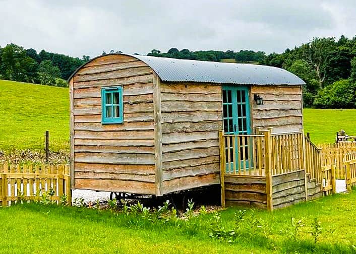 Rustic shepherd hut with private deck and open countryside outlook.