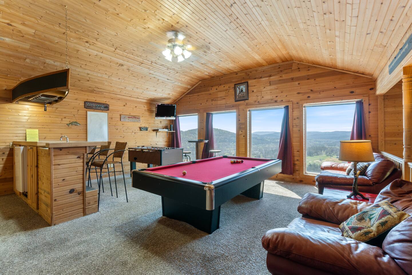On the upper level of this exquisite home you'll find a game room with large windows overlooking the beautiful river and valley views. This game room has a pool table, foosball table, bar area with mini fridge and sink, TV, and plenty of seating. 