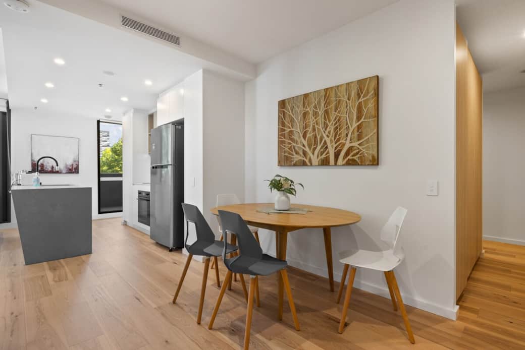 Enjoy meals at this stylish dining area, complete with a beautifully crafted wooden table, comfortable chairs, and elegant wall art that adds a natural touch.