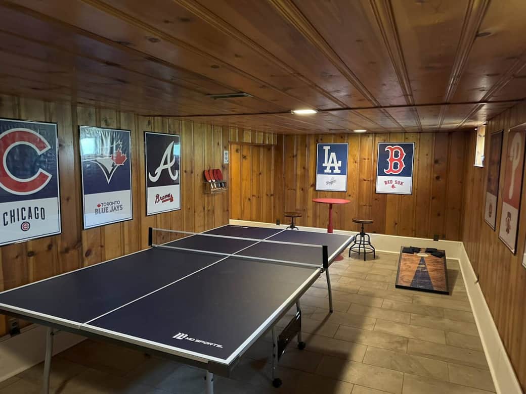 Finished basement with regulation size ping pong table and cornhole set.