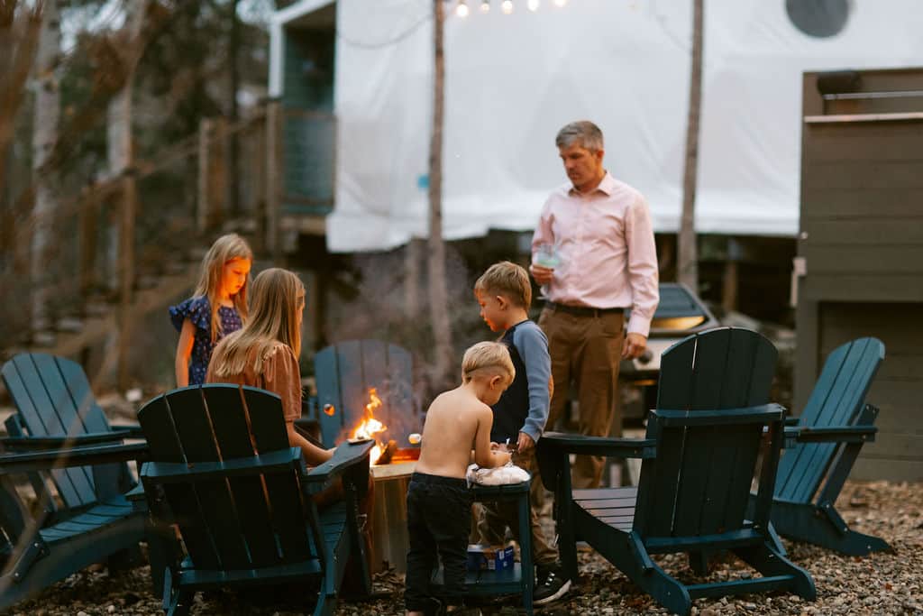 Family gathered around the fire pit at sunset at Auburn Glamping near Lake Martin