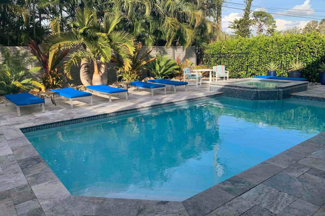 Beautiful silver travertine patio around the heated salt water pool with the spa surrounded  with exotic plants . 
