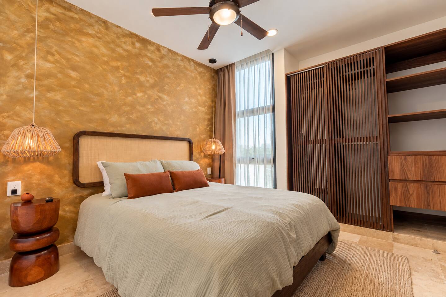 Esta recámara no solo cuenta con cama queen-size, Smart TV, aire acondicionado, ventilador de techo, amplio ropero y baño privado en suite; también incluye elegantes lámparas colgantes junto a la cama y contactos al lado de la cama para cargar tus dispositivos fácilmente.
