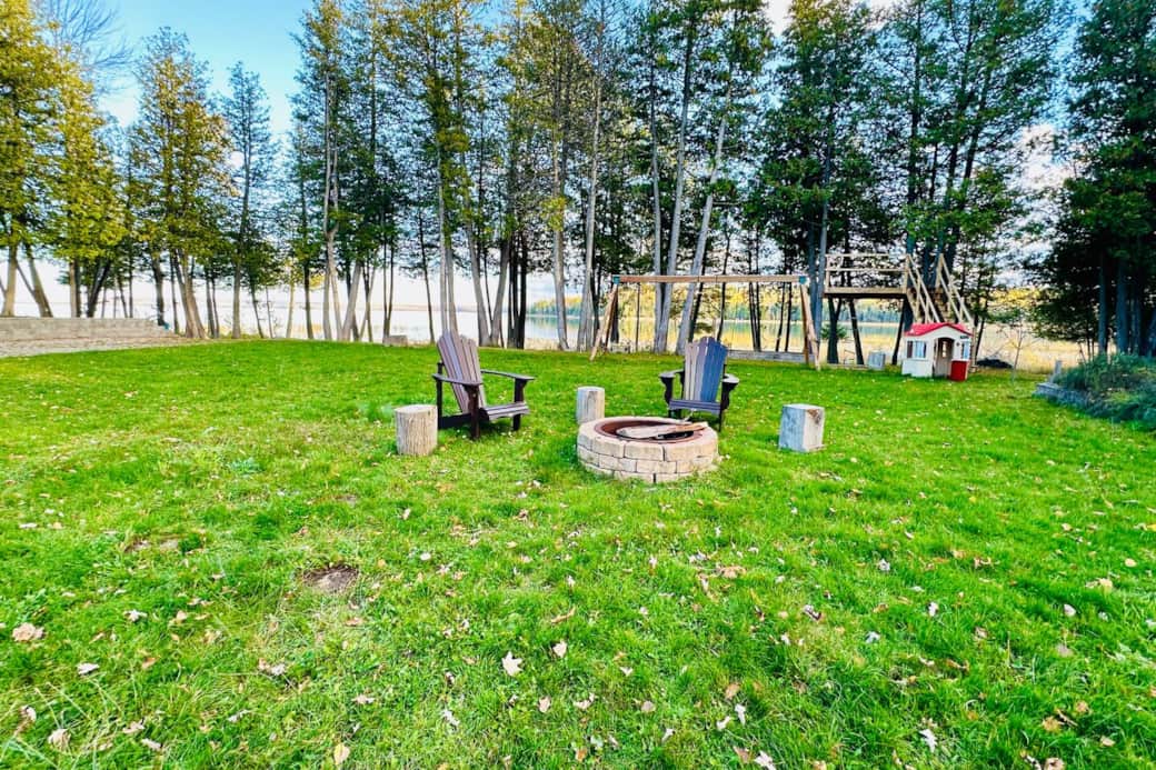 Spacious private property with firepit seating, surrounded by peaceful trees.
