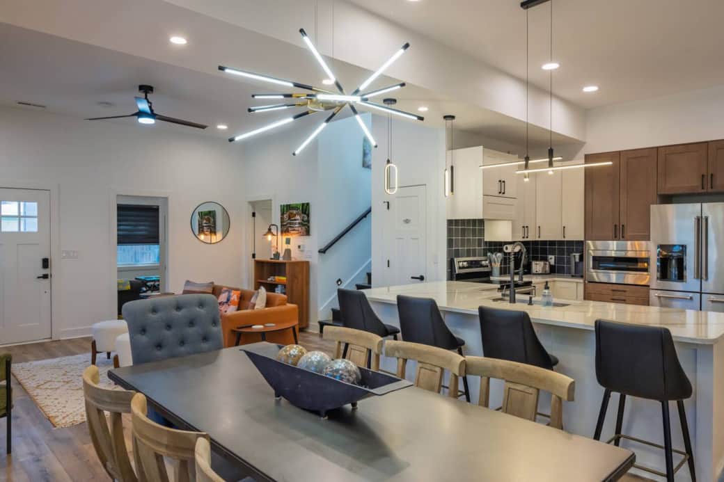 Open concept main floor. Restoration Hardware dining room set featuring distressed pine trestle base table with a zinc top. Six drifted oak side chairs upholstered in Belgian linen and two grey linen armchairs.