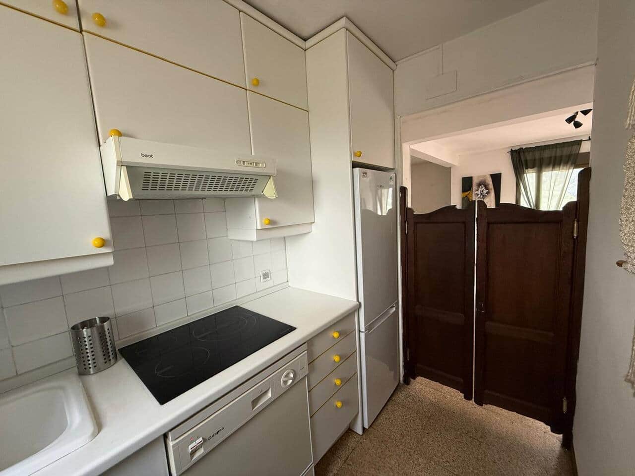 Cocina equipada con vitrocerámica, lavavajillas y nevera