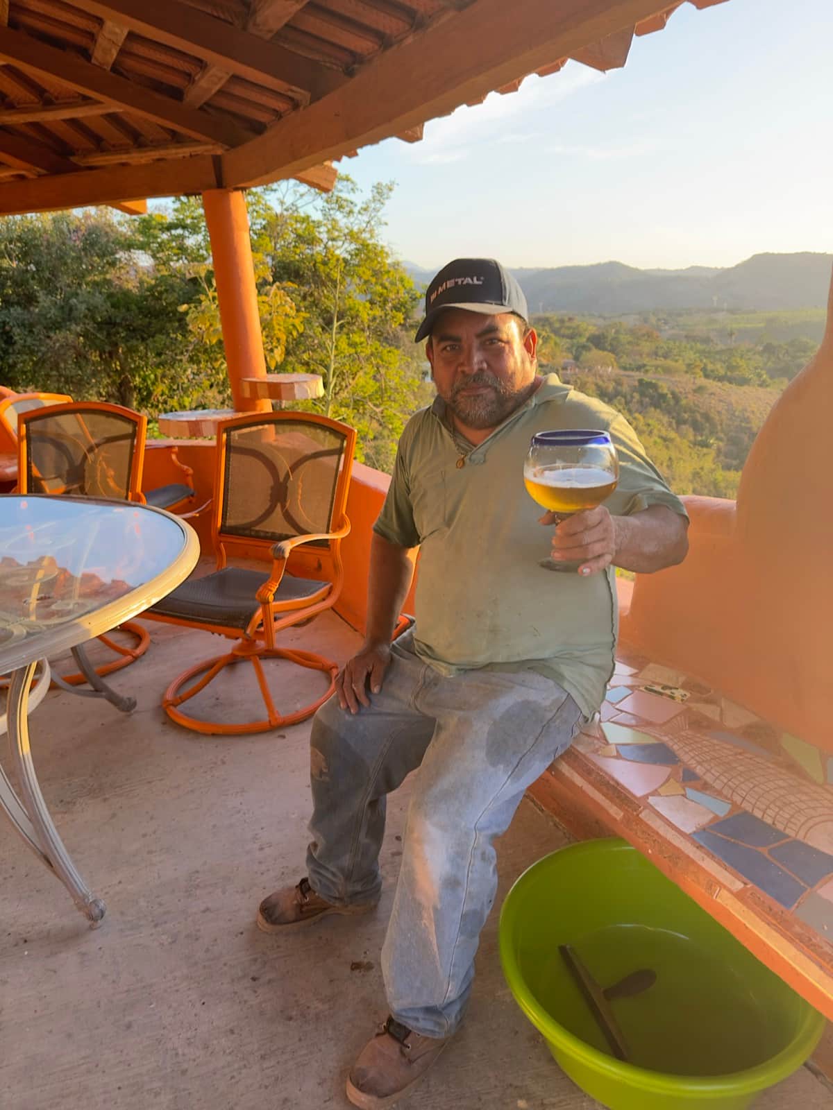Panda relaxing with a drink on the terrace at Cerrito Encantado, with the green hills behind