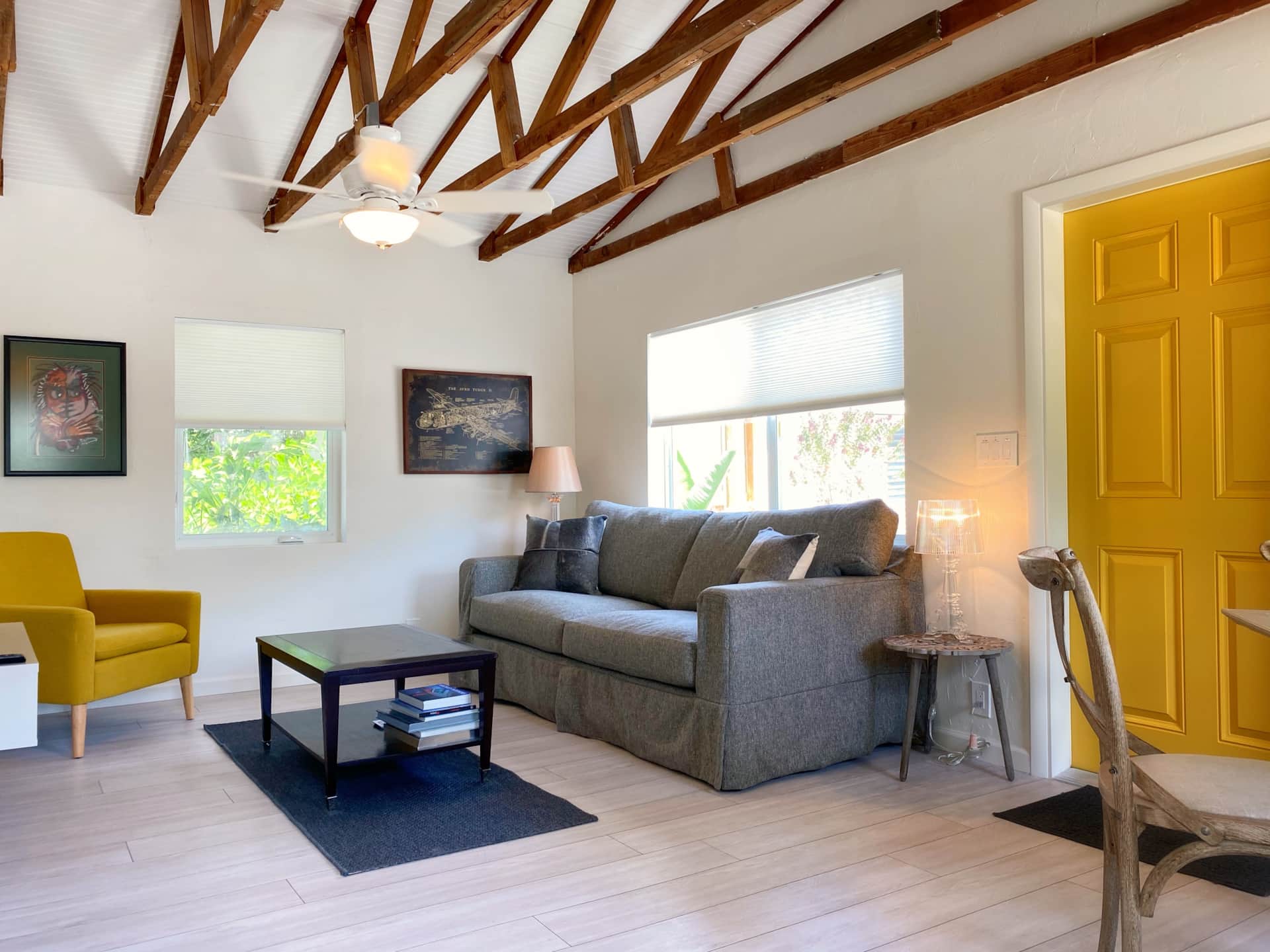 Renovated Unit 2 guest suite at Casa Citron with exposed ceiling beams, cottage-style design, and an airy, masculine interior overlooking the pool deck.