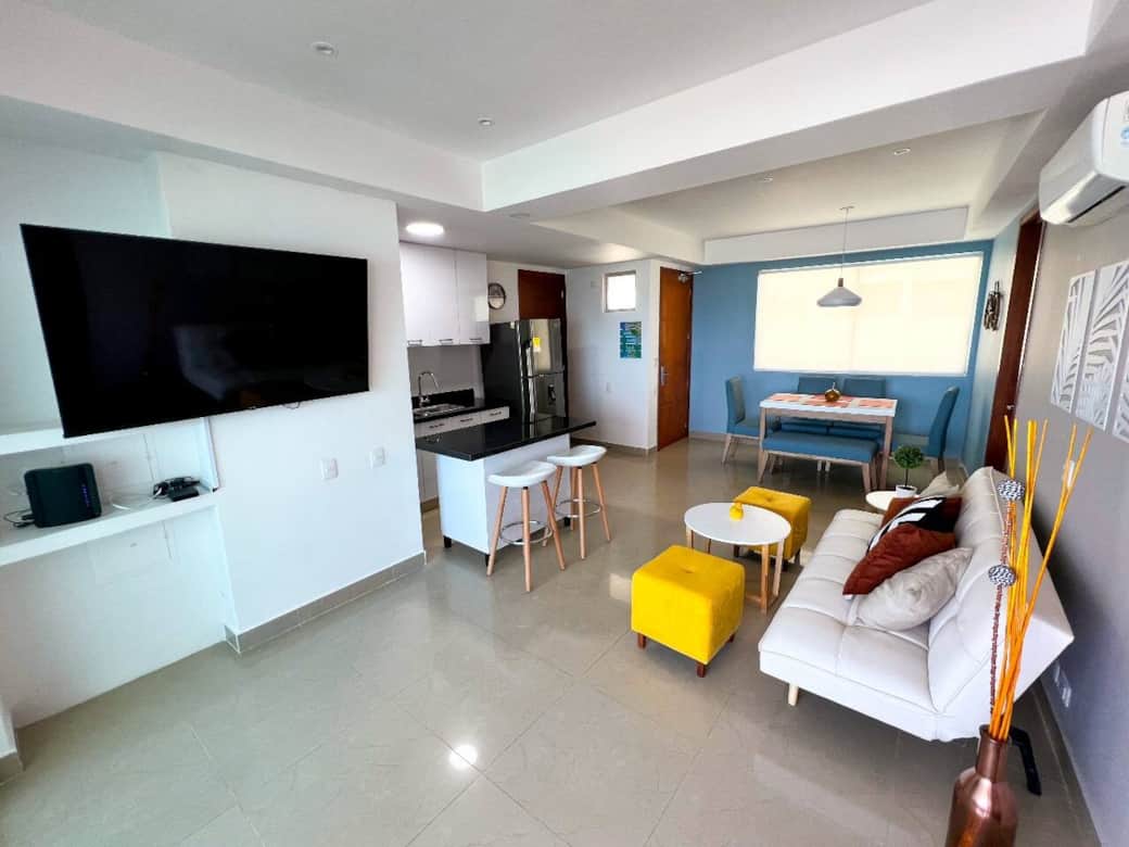 Sala amplia y luminosa con aire acondicionado, sofá cama, TV por cable y vista parcial al mar. Integrada al comedor de 6 puestos y cocina equipada, ideal para compartir momentos cómodos en familia o con amigos.