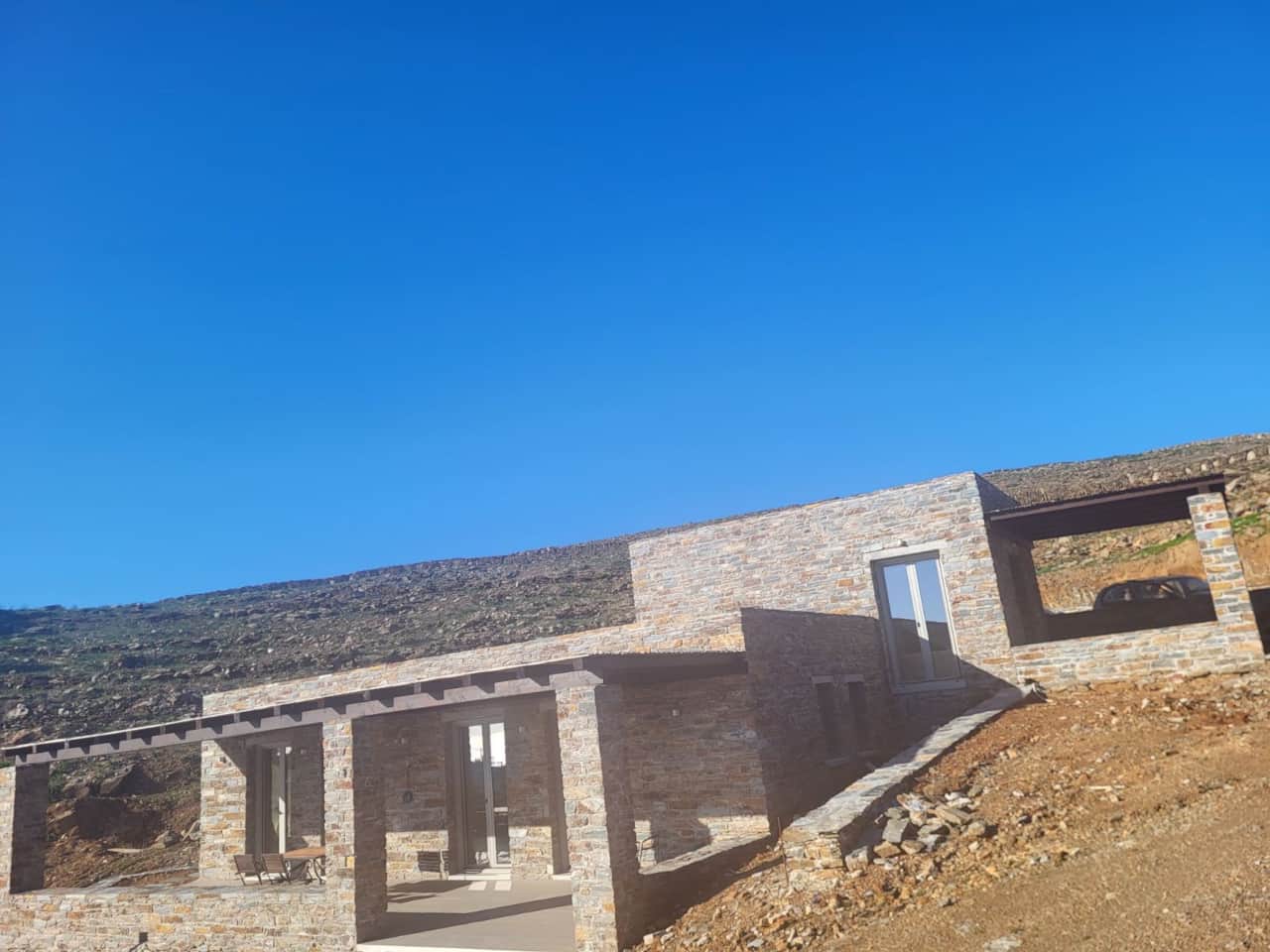 Low-angle exterior view of stone lodging against blue sky, Kea islan
