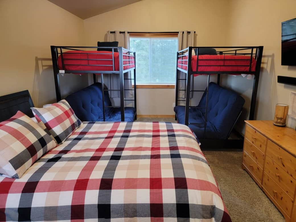 Upstairs bunk room hosts a queen bed, and 2 sets of bunk beds which have a full sized futon on the bottom, and a twin on top.  Also has a smart TV and storage for clothes.