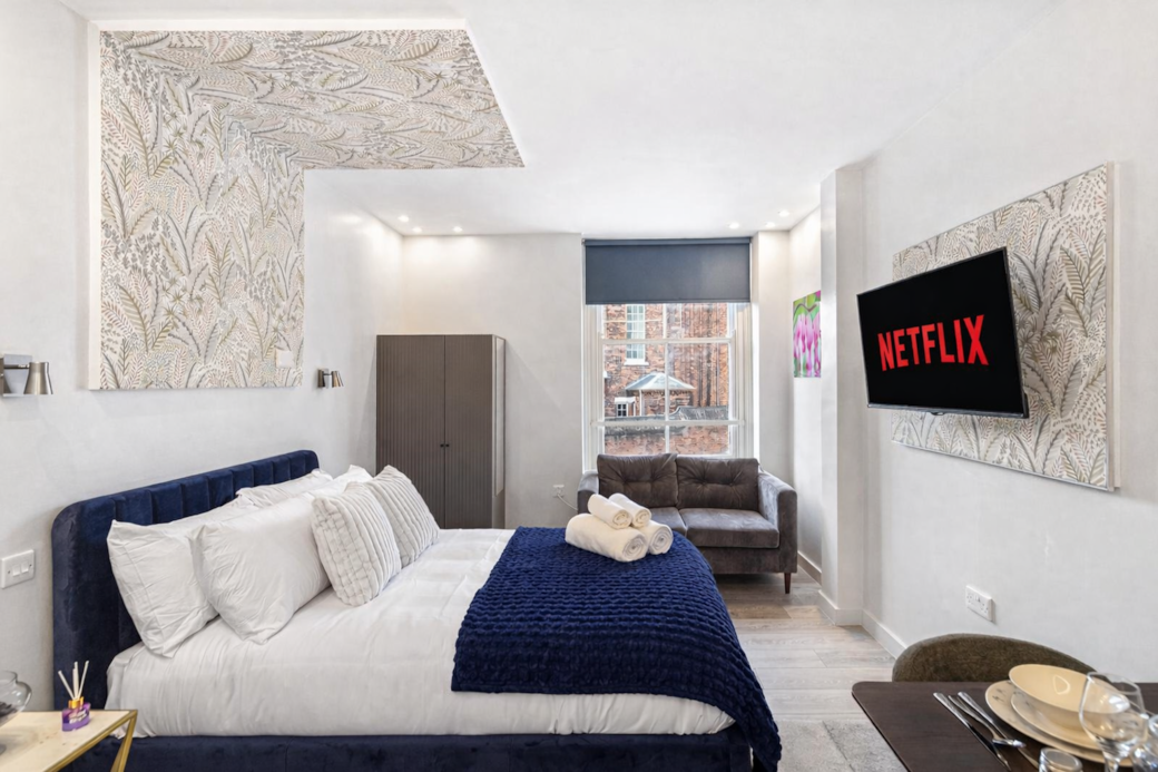 Bright and stylish bedroom featuring a plush double bed with luxury linens, feature wallpaper Bright and stylish bedroom featuring a plush double bed with luxury linens, feature wallpaper