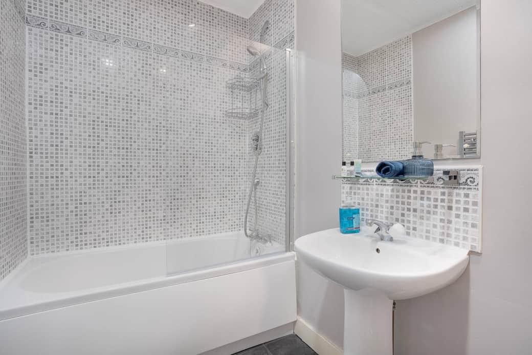 Clean, modern bathroom with a full-size bath and overhead shower, suitable for both quick mornings and relaxed evenings. Clean, modern bathroom with a full-size bath and overhead shower, suitable for both quick mornings and relaxed evenings.